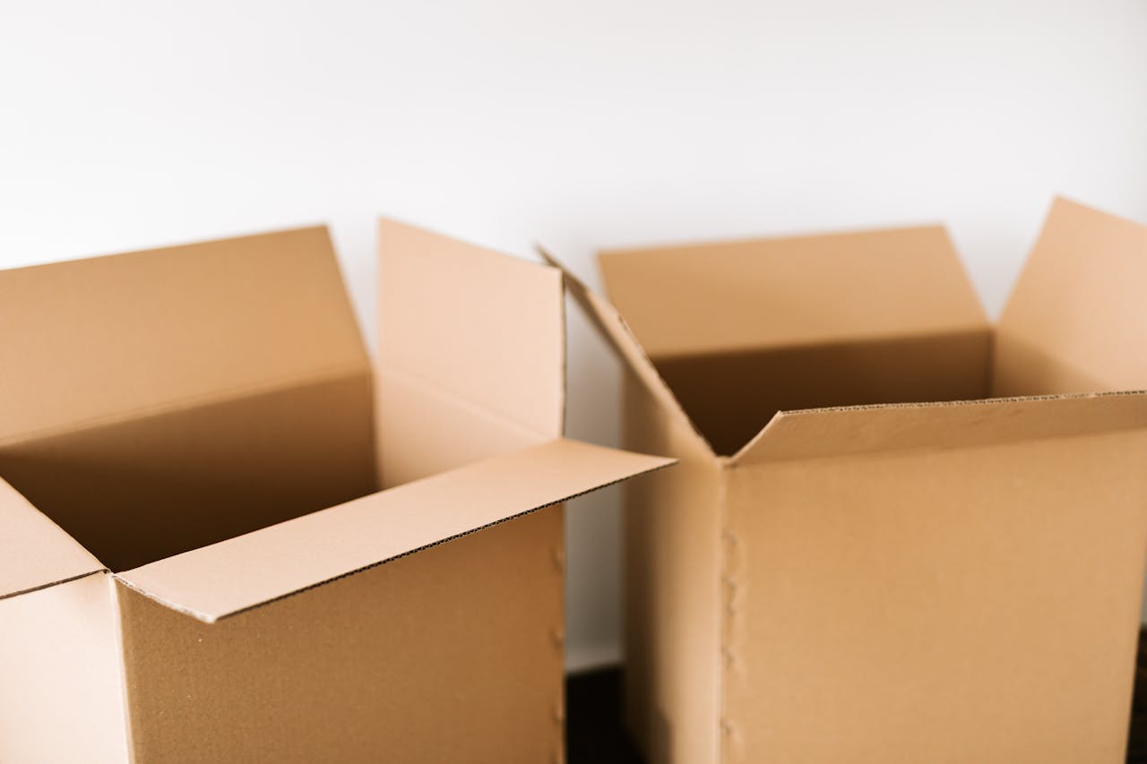 why-choose-us Opened carton boxes placed on dark surface against white plain wall in daylight before moving out