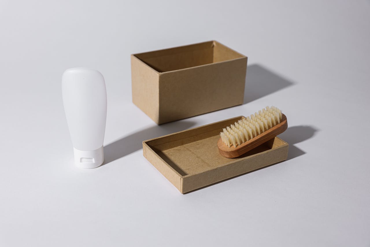 about-img A clean, minimalist mockup featuring a cardboard box, a brush, and a white bottle, ideal for product packaging concepts.